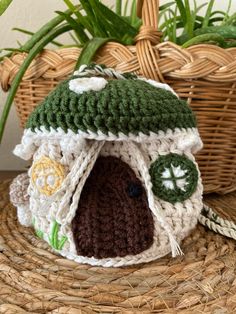 a crocheted house sitting on top of a wicker basket