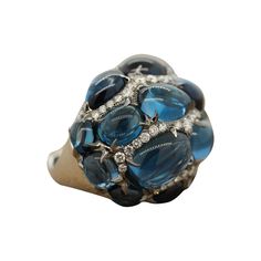 An opulent cocktail ring featuring 52.48 carats of topaz with a rich deep blue color. The cabochon oval, pear and round shaped topaz are accented by 1.70 carats of sparkling round cut diamonds. This dome shape ring is made of 18K white gold and one of a kind. Ring Size 6.5 (Sizable) Luxury Topaz Ring For Formal Events, Oval Cabochon, Luxury Cabochon Topaz Ring, Gemstone Rings Unique, Deep Blue Color, Beautiful Tiaras, Diamond Cocktail Ring, Gold Cocktail Ring, Contemporary Ring, Gold Cocktail