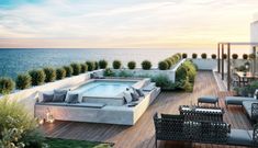 an outdoor patio with couches and tables next to the ocean