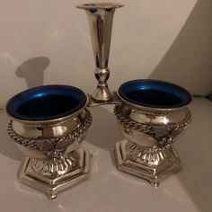 two silver candlesticks sitting next to each other on top of a white table