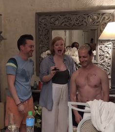 two men and a woman standing in front of a mirror with one man laughing at the camera