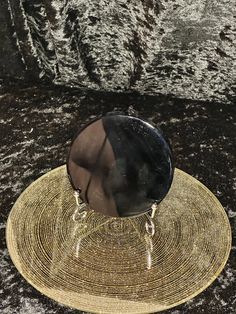 a black and gold hat sitting on top of a stone floor next to a rock