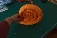 a person holding an orange object on top of a table