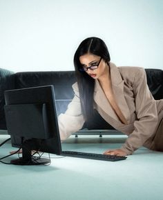 a woman sitting on the floor in front of a computer