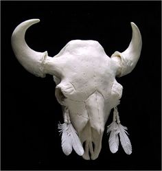 a white cow skull with feathers on it's head and two horns that have been cut out