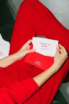 a woman in red is holding some cards