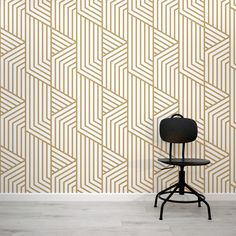 a chair sitting in front of a wall with a geometric pattern on the wall behind it