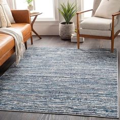 a living room area with two couches and a rug on the floor in front of a window