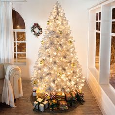 a white christmas tree with presents under it