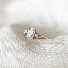 an engagement ring sitting on top of a white cloth covered bed sheet, with three diamonds in the middle