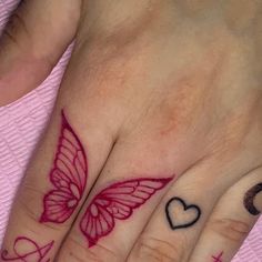 two hands with hearts and a butterfly tattoo on their fingers, both holding each other