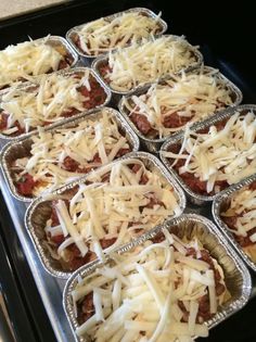 many trays of food with cheese on top of them in the oven, ready to be cooked