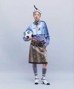 a woman is holding a soccer ball and wearing a skirt with an animal print on it