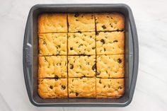 a baking pan filled with squares of chocolate chip cookie bars on top of a white counter