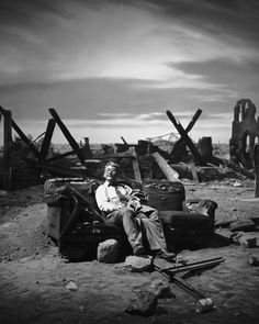 a man sitting on top of a chair in front of a pile of rubbles