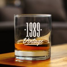 an old fashioned whiskey glass sitting on top of a wooden table next to a couch