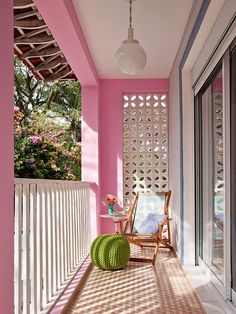 a pink and white porch with a green chair on the front door, and a light fixture hanging from the ceiling