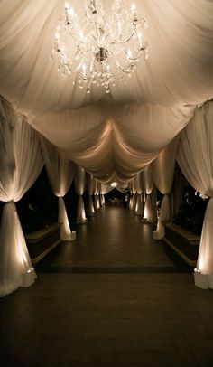 an image of a wedding venue with white drapes and chandelier