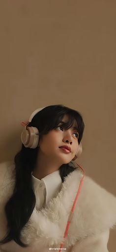 a woman with headphones on her ears is wearing a fur coat and looking off to the side