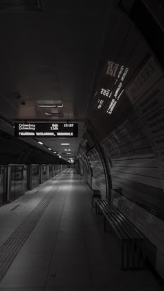 an empty subway station with benches and signs on the walls in black and white colors