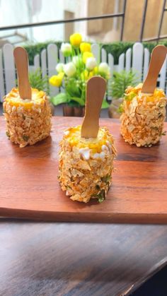 four appetizers are sitting on a cutting board with toothpicks sticking out of them