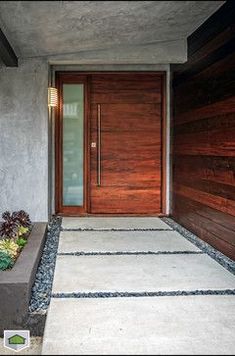 the entrance to a modern home with wooden doors