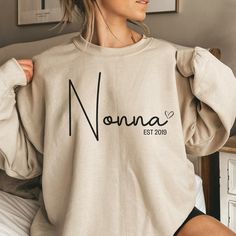 "Introducing our Custom Nonna Sweatshirt, the perfect holiday gift for your beloved Nonna! Made with love and care, this sweatshirt is an ideal Mothers Day gift for nonnas or a heartwarming present for any occasion. Our sweatshirt is comfortable and stylish, featuring a unique design that proudly displays the title \"Nonna.\" Perfect for pregnancy reveals or as a gift from the grandkids, this Nonna shirt is sure to bring a smile to her face. Treat your Nonna to something special and show her how Nonna Gifts, Gift From Grandkids, Mama Sweater, Mama Hoodie, Mommy Outfits, New Grandparents, New Grandma, Kids Names, Nana Gifts