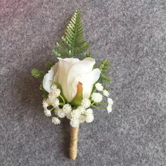 a boutonniere with white flowers and greenery