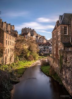 a river running through a small town with tall buildings on the top of it's sides