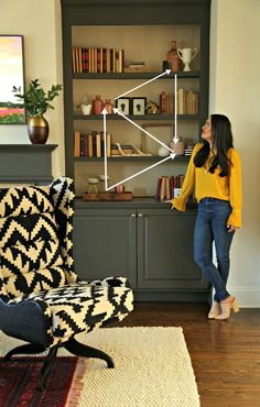 a woman standing in front of a book shelf with books on it and a chair