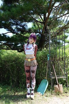 a woman with purple hair and tattoos standing next to a tree