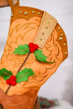 a cowboy boot with holly leaves and red berries on the inside, hanging from a hook