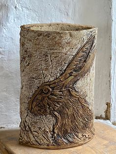 a close up of a vase on a table with a white wall in the background