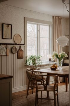 a dining room table and chairs with vases on the table in front of it