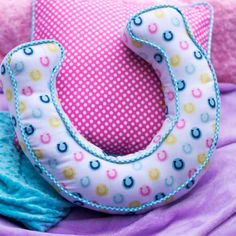 a close up of a pillow on a bed with a horse shoe shaped pillow in the middle