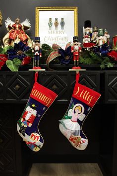 two christmas stockings hanging from a fireplace mantel with decorations on it and a framed photo in the background