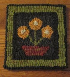 a close up of a rug on a wooden floor with flowers in a vase and leaves