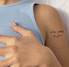 a woman wearing a blue tank top with writing on her arm and the words, one point at your chest