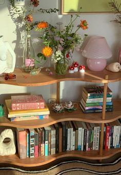 a bookshelf filled with lots of books next to a vase full of flowers