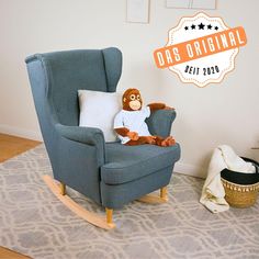 a blue rocking chair with a stuffed monkey sitting on it's back in front of a white wall