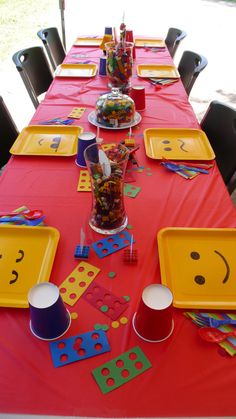 a table set up for a birthday party with plates and cups filled with candies