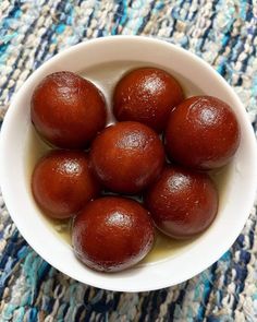 a white bowl filled with red fruit on top of a blue rug