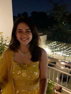 a woman in a yellow dress standing on a balcony