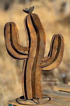 a metal cactus with a bird perched on it's top sitting on a wooden table