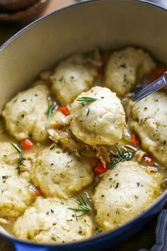 some dumplings are being cooked in a blue pot with a ladle full of them