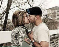 a man and woman kissing each other in front of some trees on a snowy day