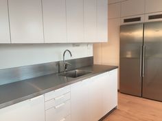 an empty kitchen with stainless steel appliances and white cupboards on either side of the sink