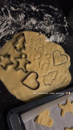 cookie cutters shaped like christmas trees and hearts on a baking sheet next to an uncooked cookie