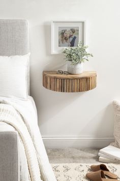 a bedroom with white walls and a small wooden shelf on the wall next to a bed