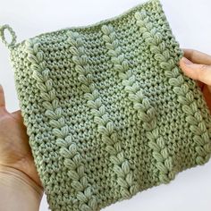 someone is holding up a green crocheted pouch